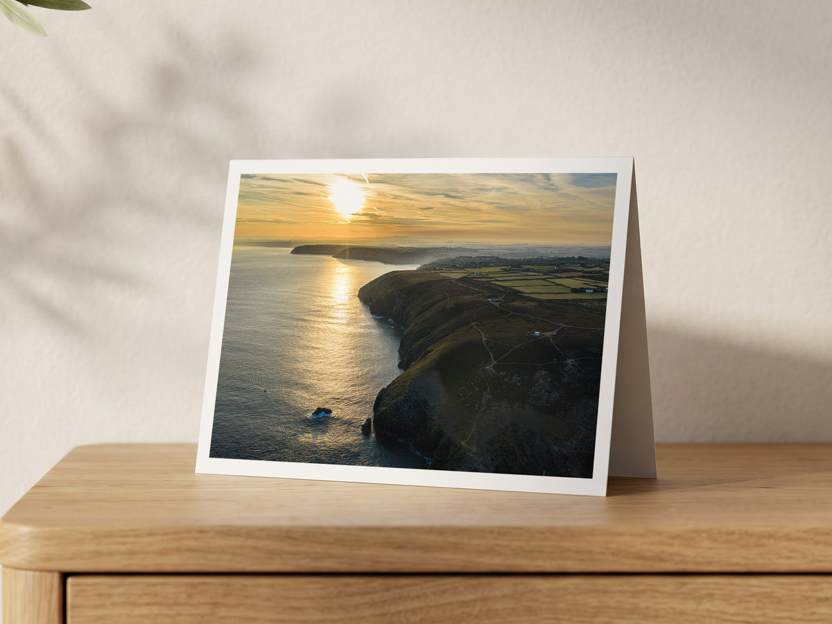 Premium A5 greeting card showing the sun rising over the sea beside St Agnes Head, looking north-east up the coast