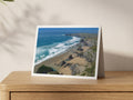 Premium A5 greeting card showing the Bedruthan Steps sea stacks exposed on wide sand at low tide, with lines of surf