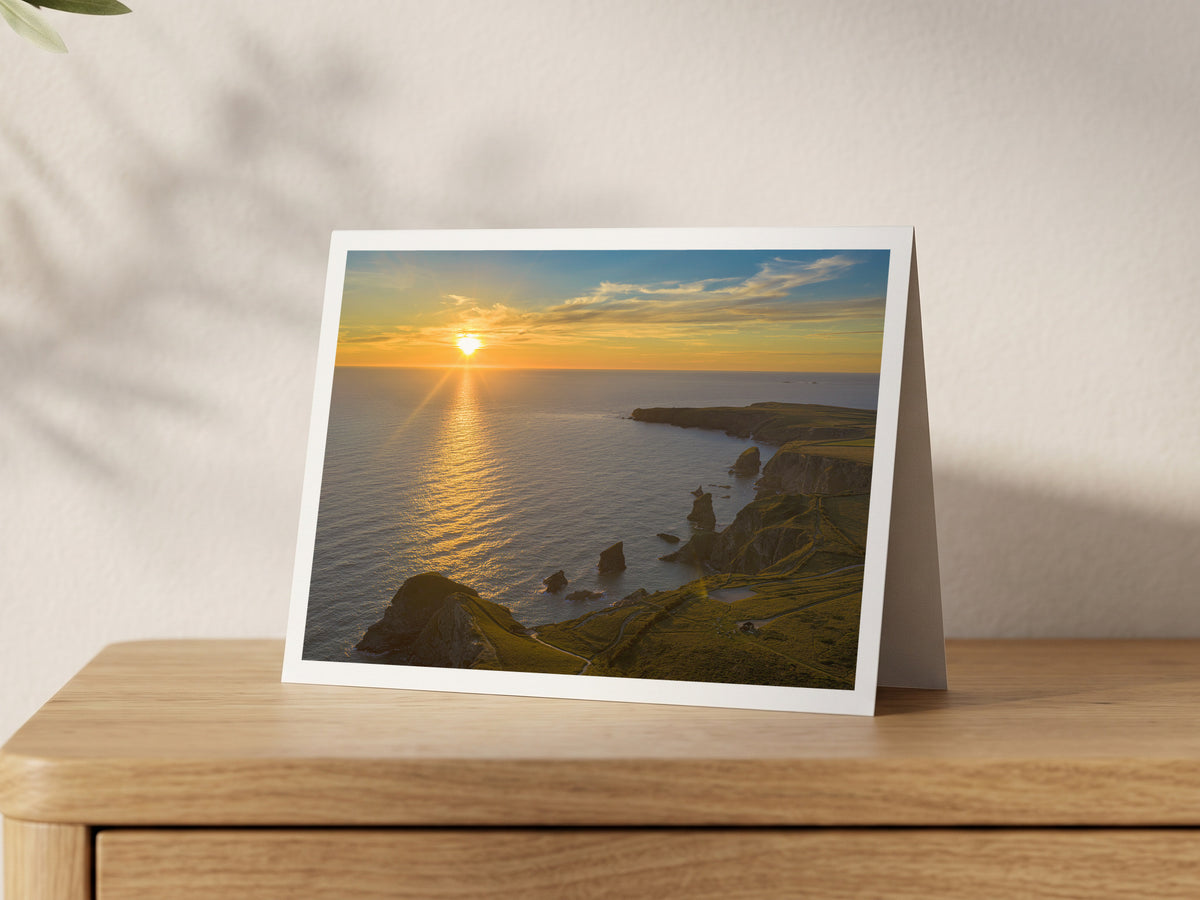 Premium A5 greeting card showing the sun setting over the sea beyond the Bedruthan Steps stacks at high tide
