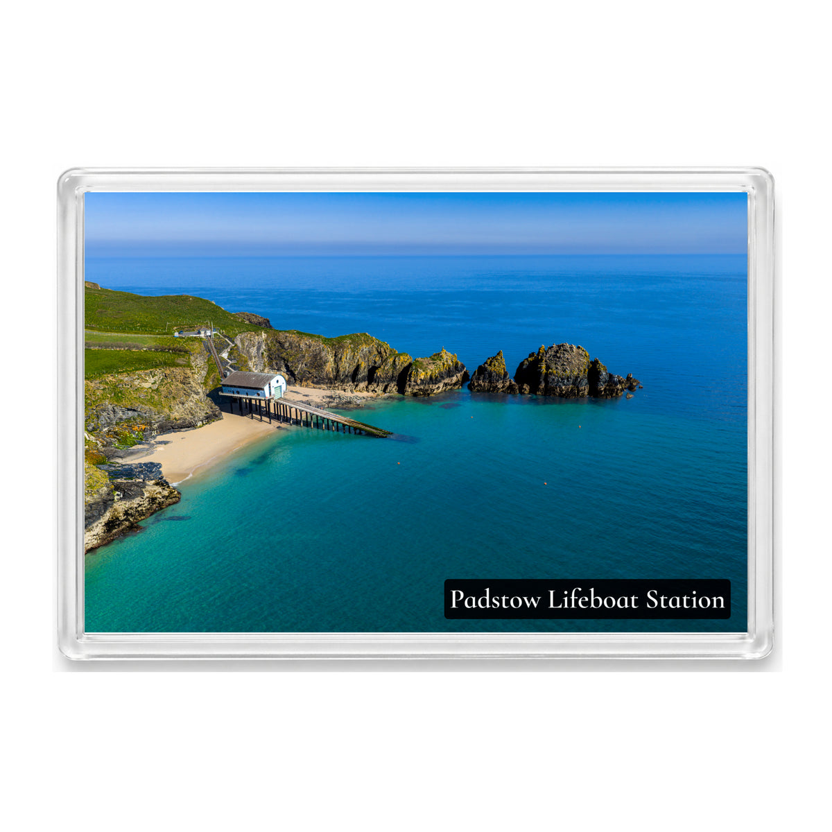 Padstow Lifeboat Station fridge magnet showing the station and slipway at Mother Ivey’s Bay beside turquoise water and rocky islets