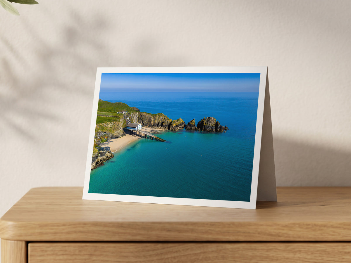 Premium A5 greeting card showing Padstow Lifeboat Station and its slipway at Mother Ivey’s Bay beside turquoise water and rocky islets