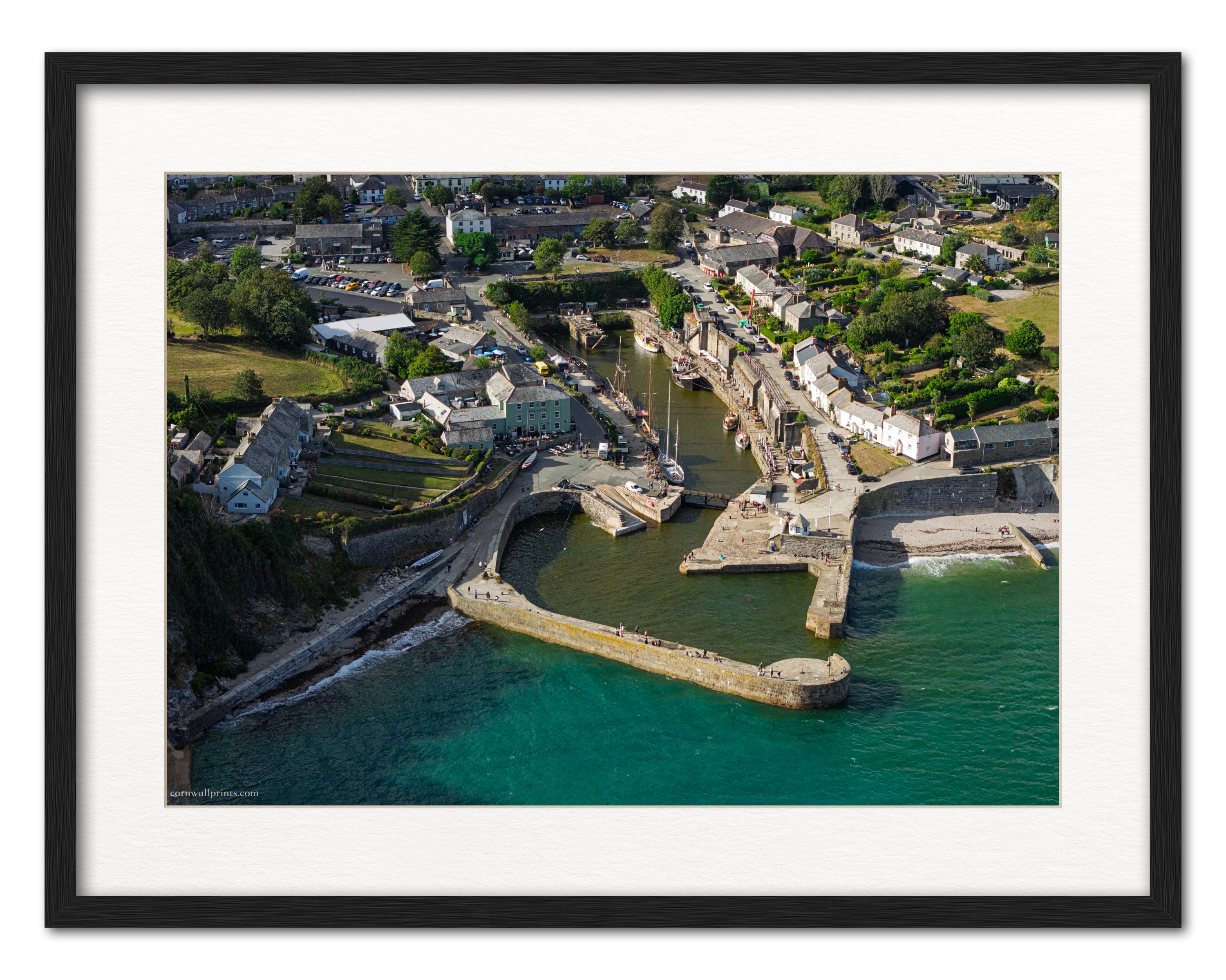 Charlestown Harbour aerial photograph showing tall ships, stone piers and contrasting turquoise sea, displayed in a black frame with white mount
