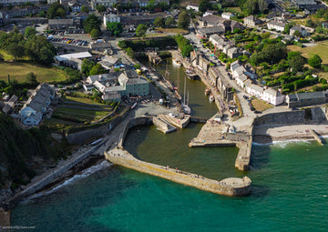 Close aerial view of Charlestown Harbour with traditional sailing vessels, stone piers and muted run-off water contrasting with the turquoise sea
