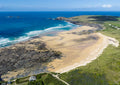 Aerial view of Constantine Bay and Booby’s Bay joined at low water on a big spring tide, with offshore swell breaking beneath Trevose Head and its lighthouse.