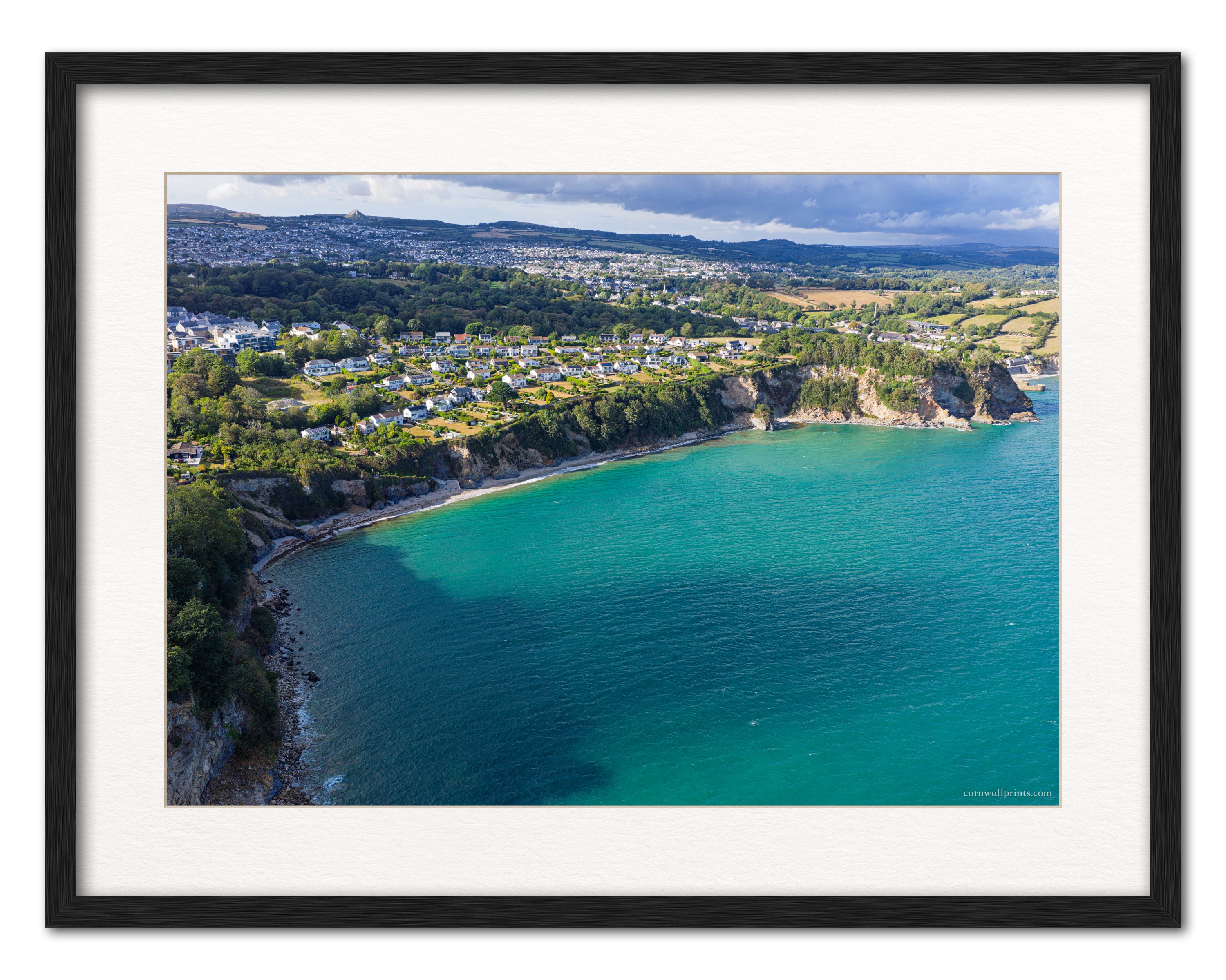 Duporth Beach aerial photograph with turquoise St Austell Bay, coastal homes and St Austell beyond, displayed in a black frame with white mount
