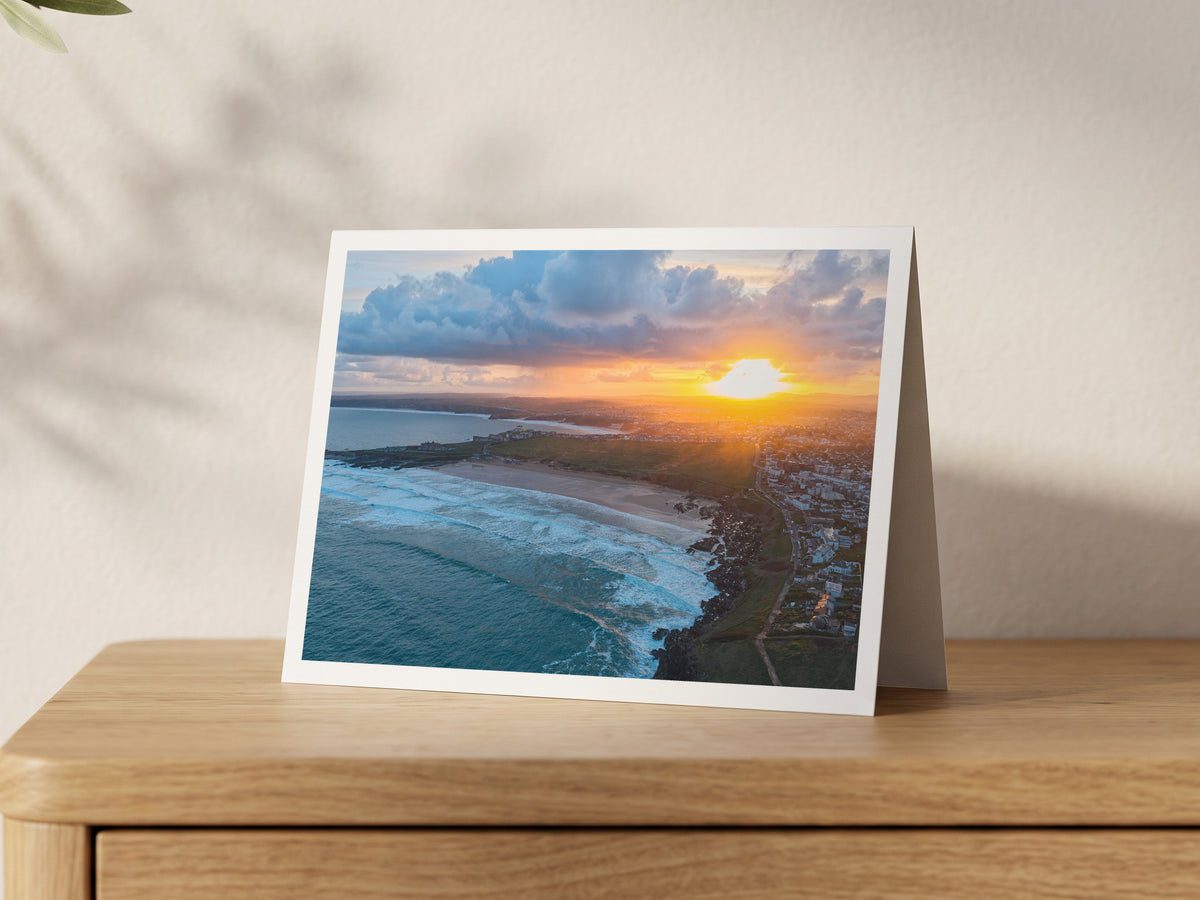 Premium A5 greeting card showing sunrise over Newquay with Atlantic surf rolling into Fistral Beach