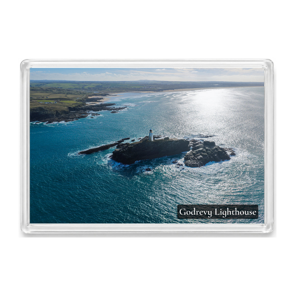 Godrevy Lighthouse on its rocky island with brilliant autumn sunlight on the sea and the coast towards Gwithian behind it, shown in a clear acrylic fridge magnet with a Godrevy Lighthouse label
