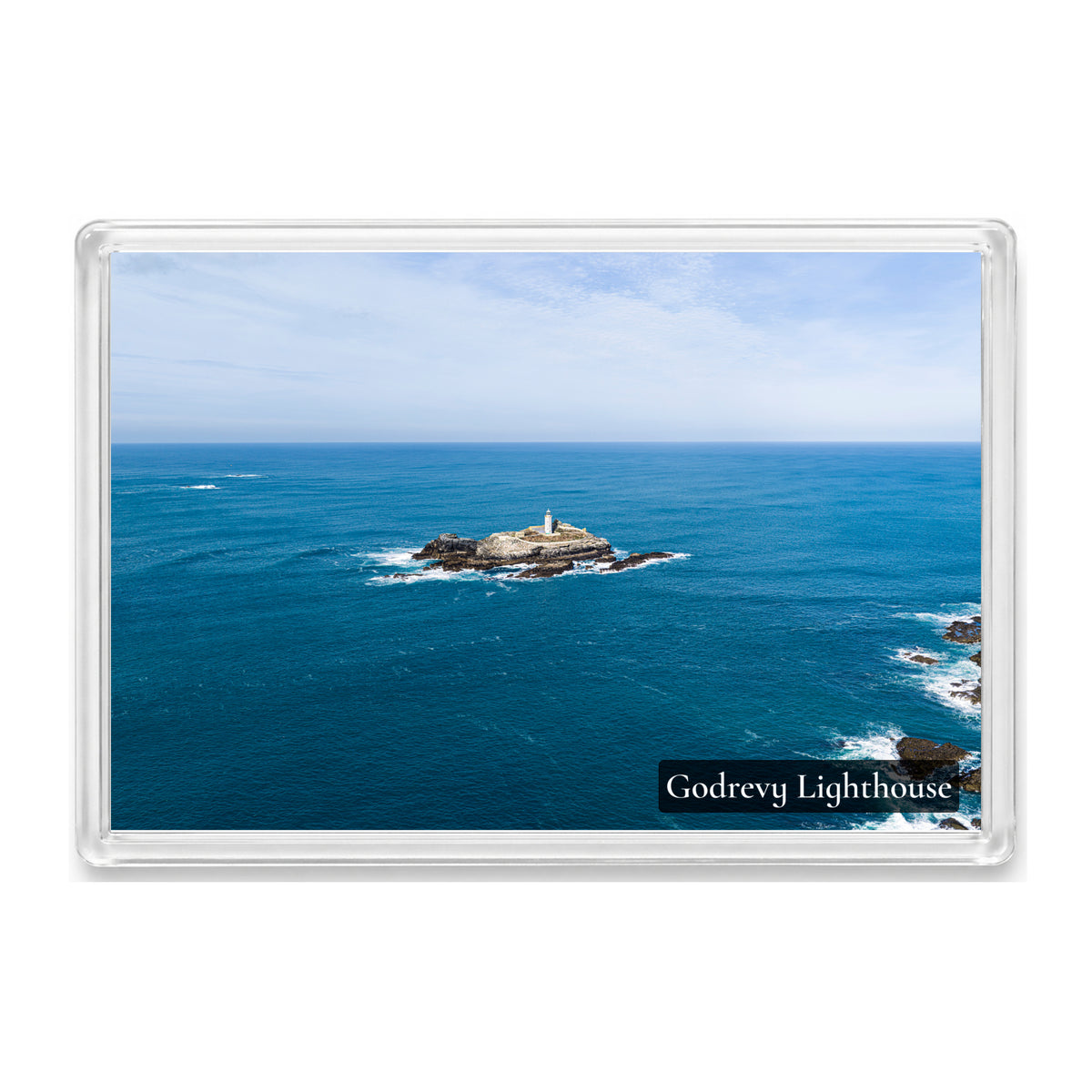 Godrevy Lighthouse isolated on its rocky island in a wide expanse of blue sea beneath a pale sky, shown in a clear acrylic fridge magnet with a Godrevy Lighthouse label
