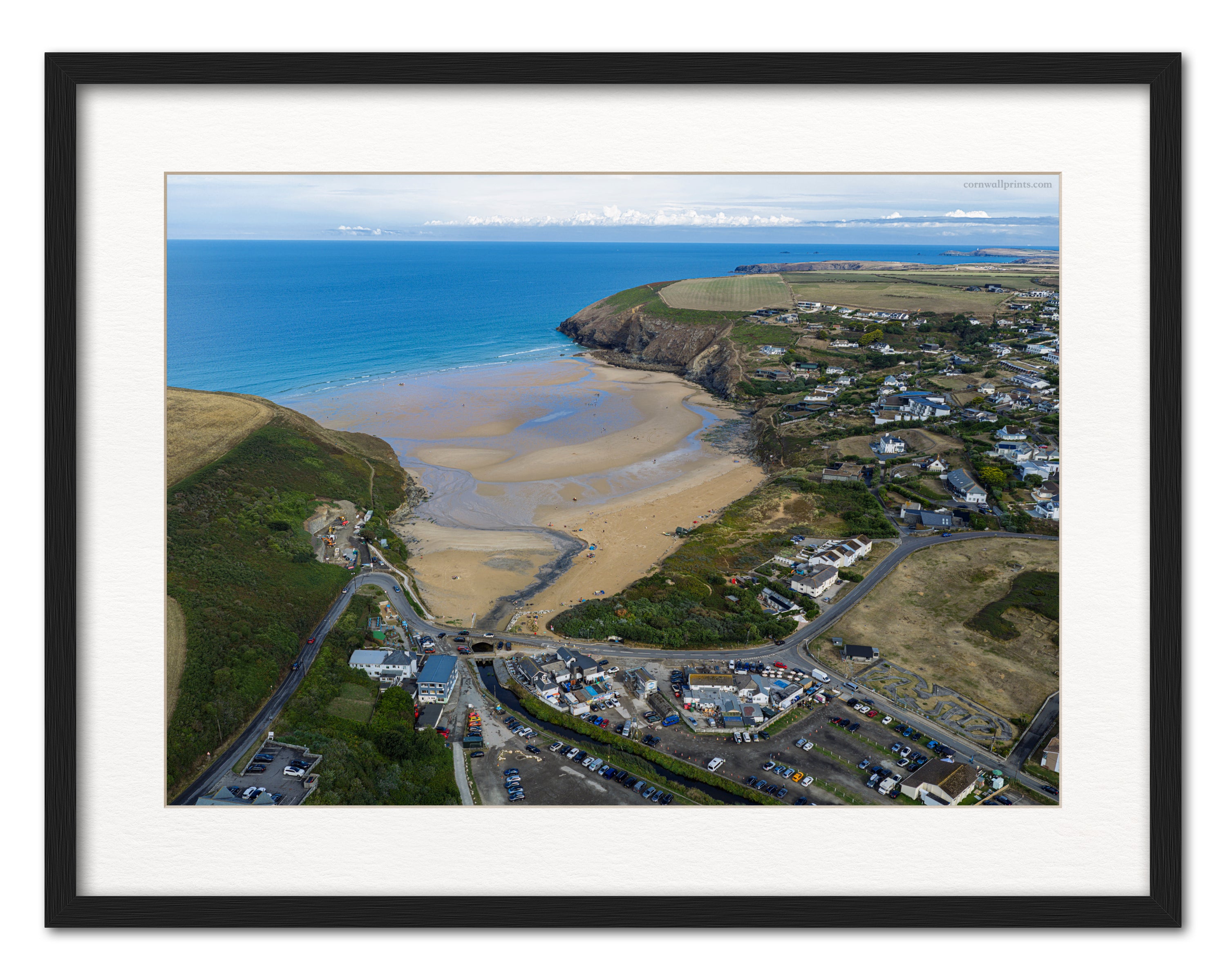 Mawgan Porth aerial photograph of the low-tide beach, village and headlands displayed in a black frame with white mount