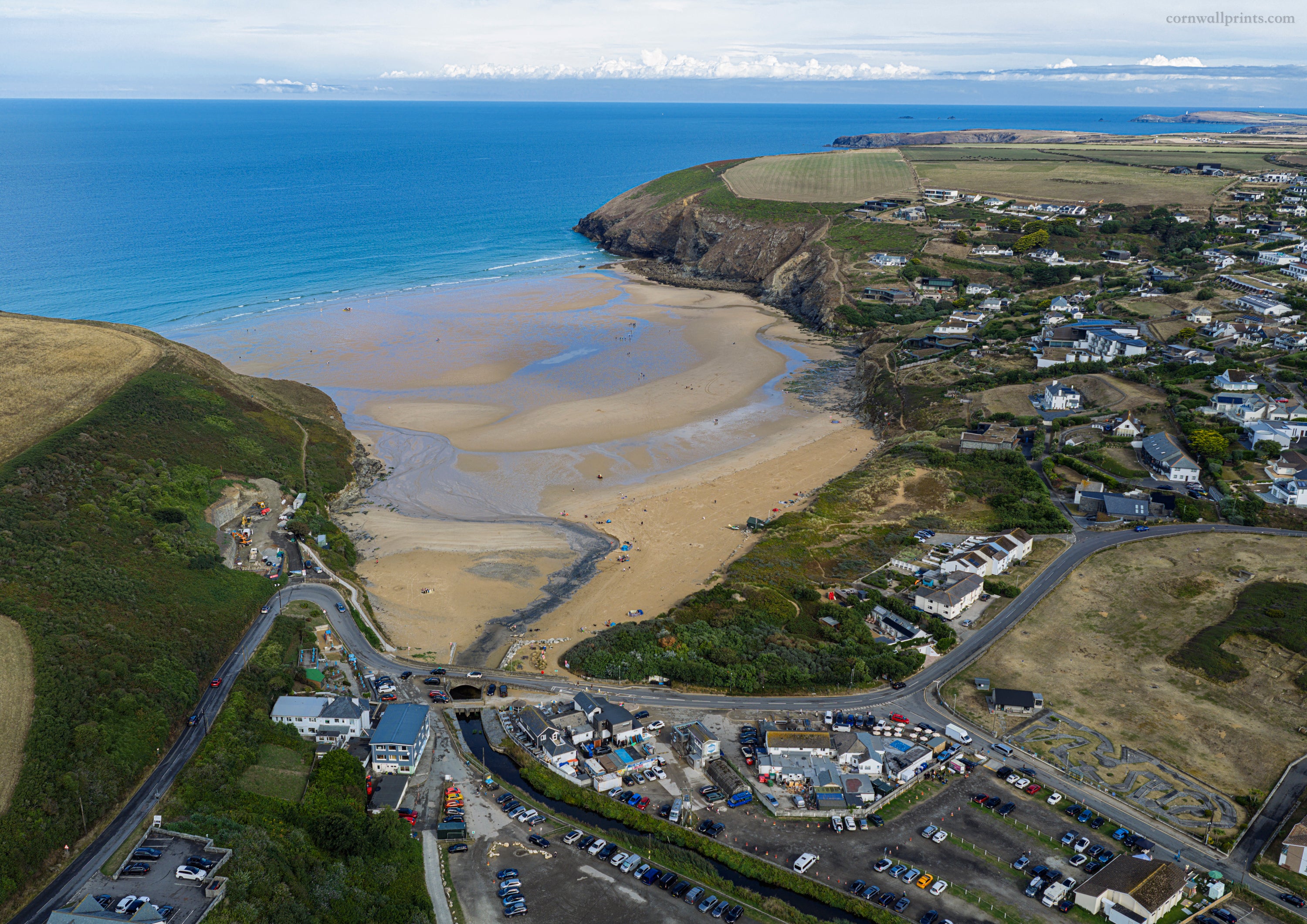 Aerial view of Mawgan Porth at low tide with the River Menalhyl crossing the beach, village and headlands
