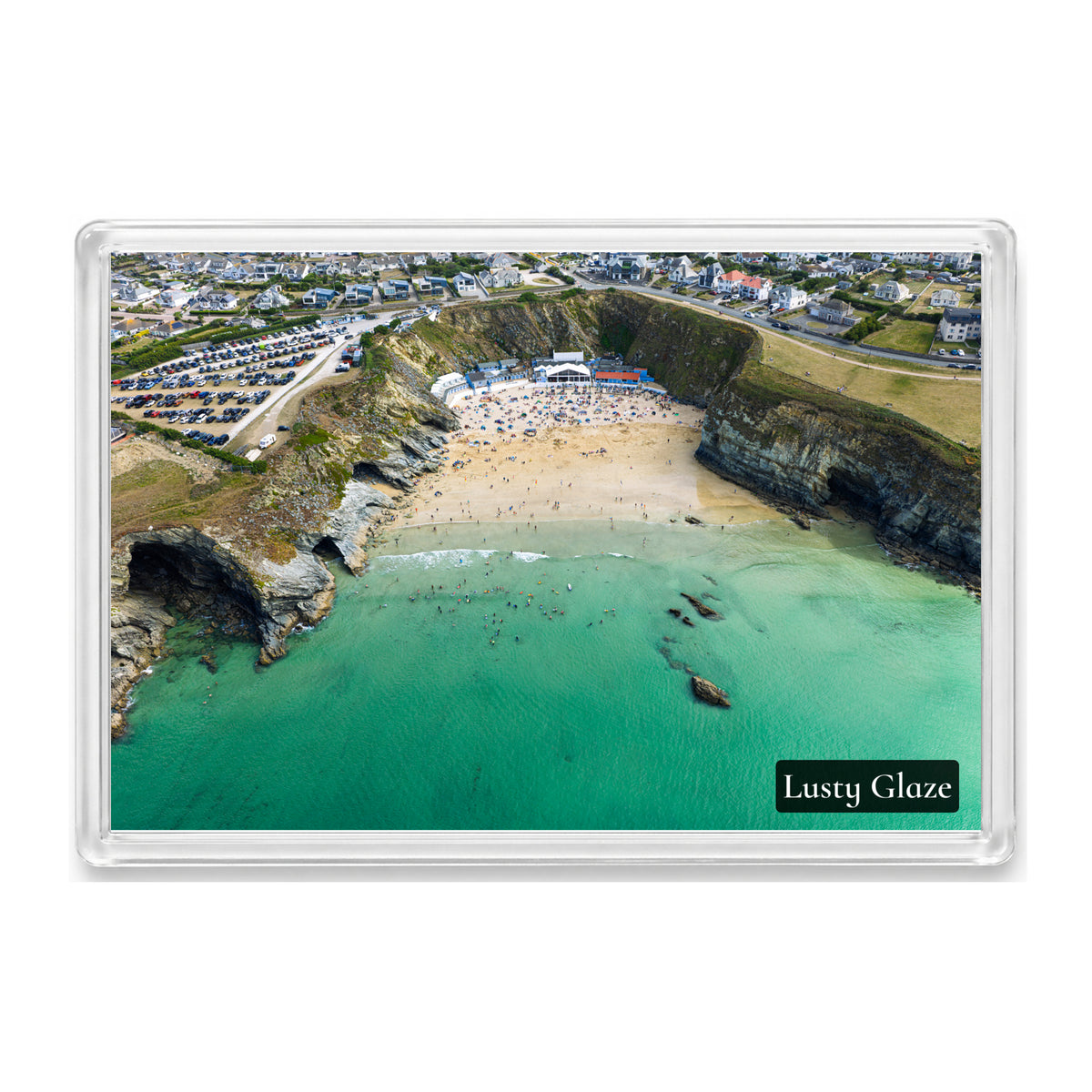 Lusty Glaze Beach fridge magnet showing swimmers and bodyboarders in green-blue water below steep cliffs and beachfront buildings