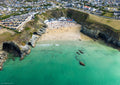 Aerial view of Lusty Glaze Beach, Newquay, with clear green-blue water, swimmers and the sheltered sandy cove at mid tide
