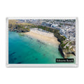 Tolcarne Beach fridge magnet showing turquoise water, a crescent of pale sand, swimmers, beach huts and Newquay above the cliffs