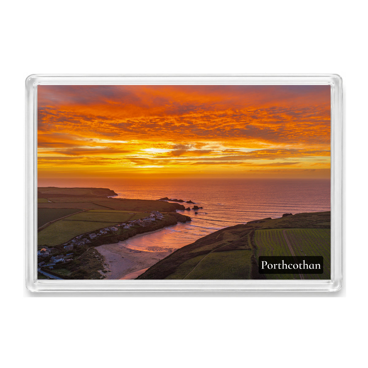 Porthcothan sunset in orange and gold over the bay and beach, with a Porthcothan label, inside a clear acrylic fridge magnet.