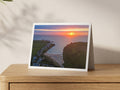 Premium A5 greeting card showing an orange sun low over Porthcothan Bay at high tide