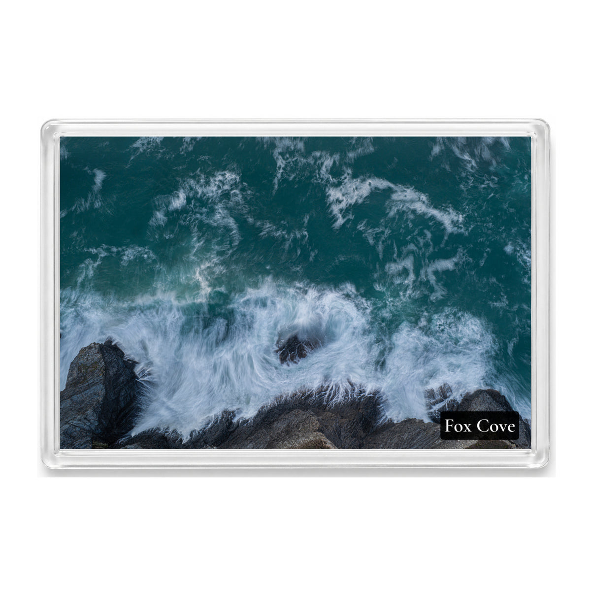 Fox Cove fridge magnet showing slow-shutter surf streaking around a lone rock and over dark layered rocks in deep teal water