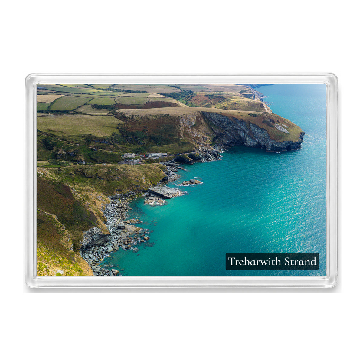 Trebarwith Strand fridge magnet showing turquoise water along the rocky shore beneath towering cliffs and sunlit clifftop fields