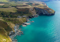 Aerial view of Trebarwith Strand with turquoise water, rugged cliffs and clifftop fields in North Cornwall.