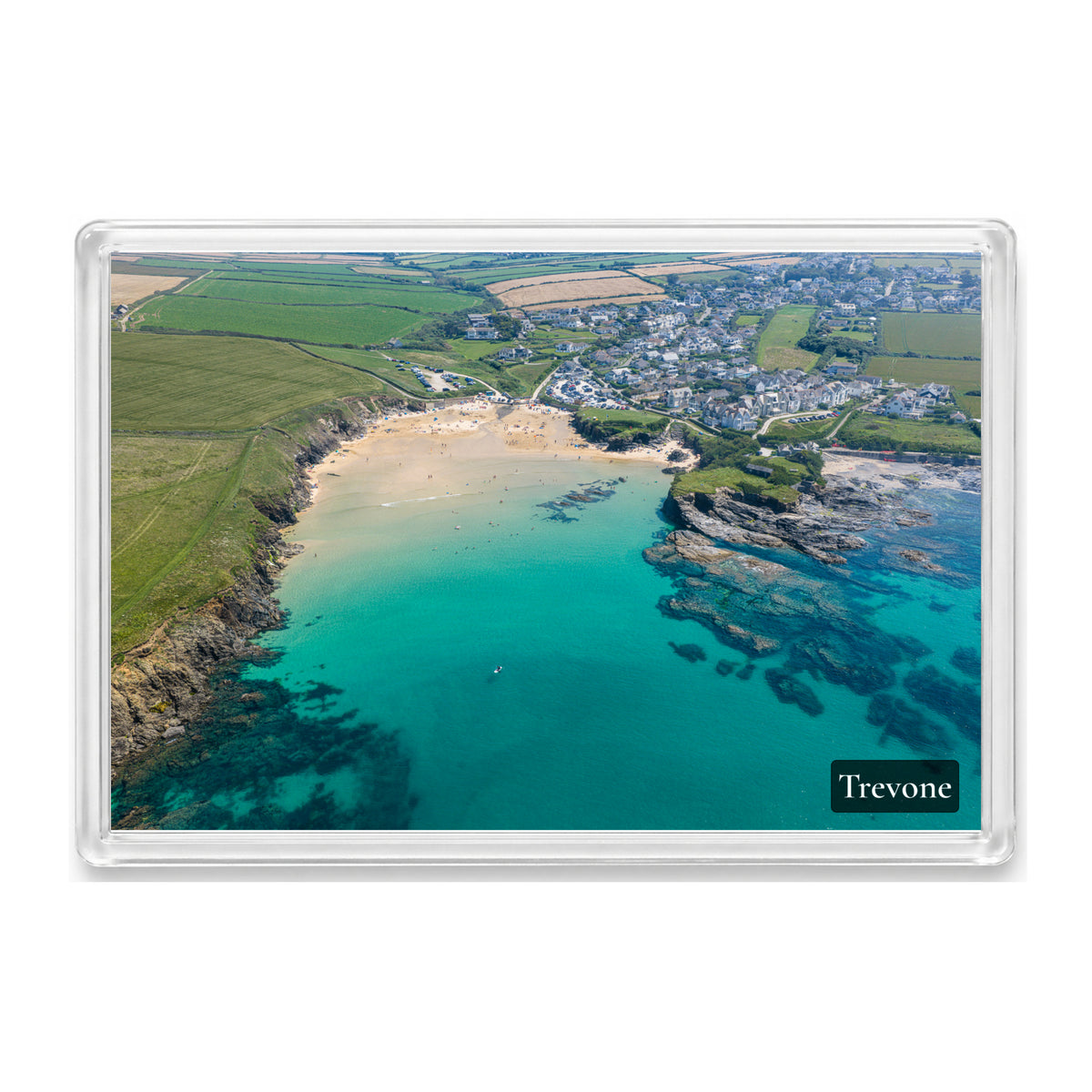 Trevone fridge magnet showing clear turquoise water over dark reef in Trevone Bay with the village around the sand on a bright summer day
