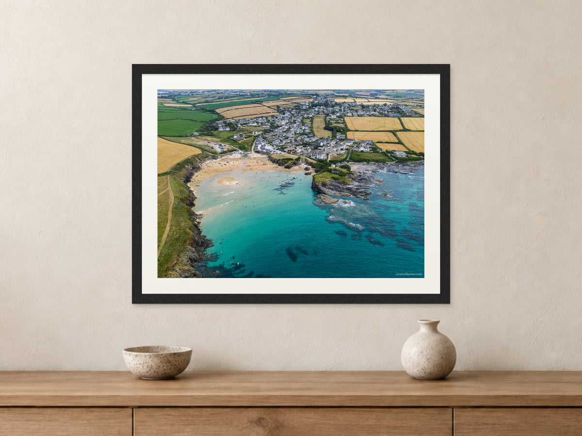 Trevone Bay and turquoise water, shown in a black frame with a white mount