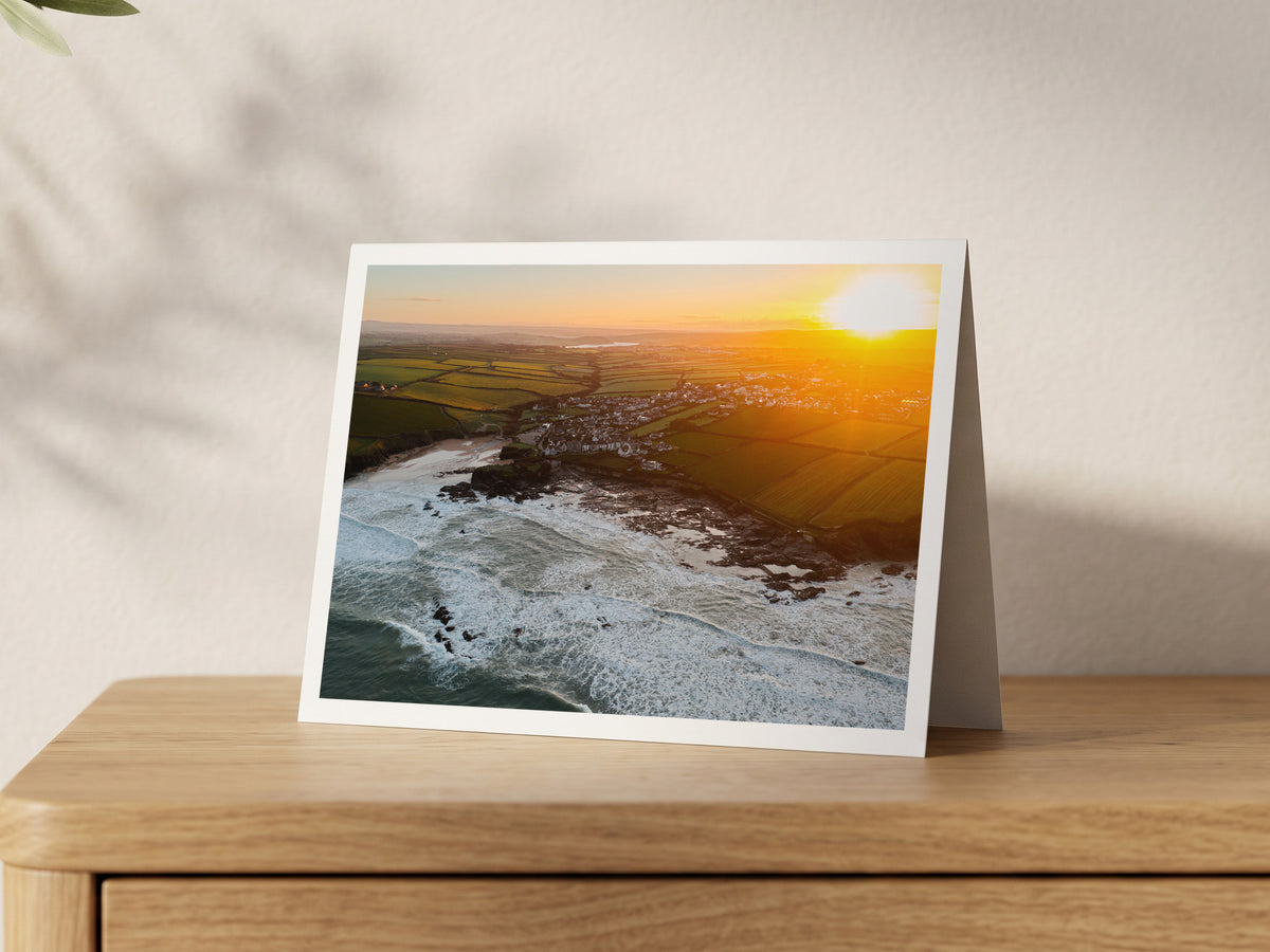 Premium A5 greeting card showing a golden sunrise over Trevone Bay, village and surf