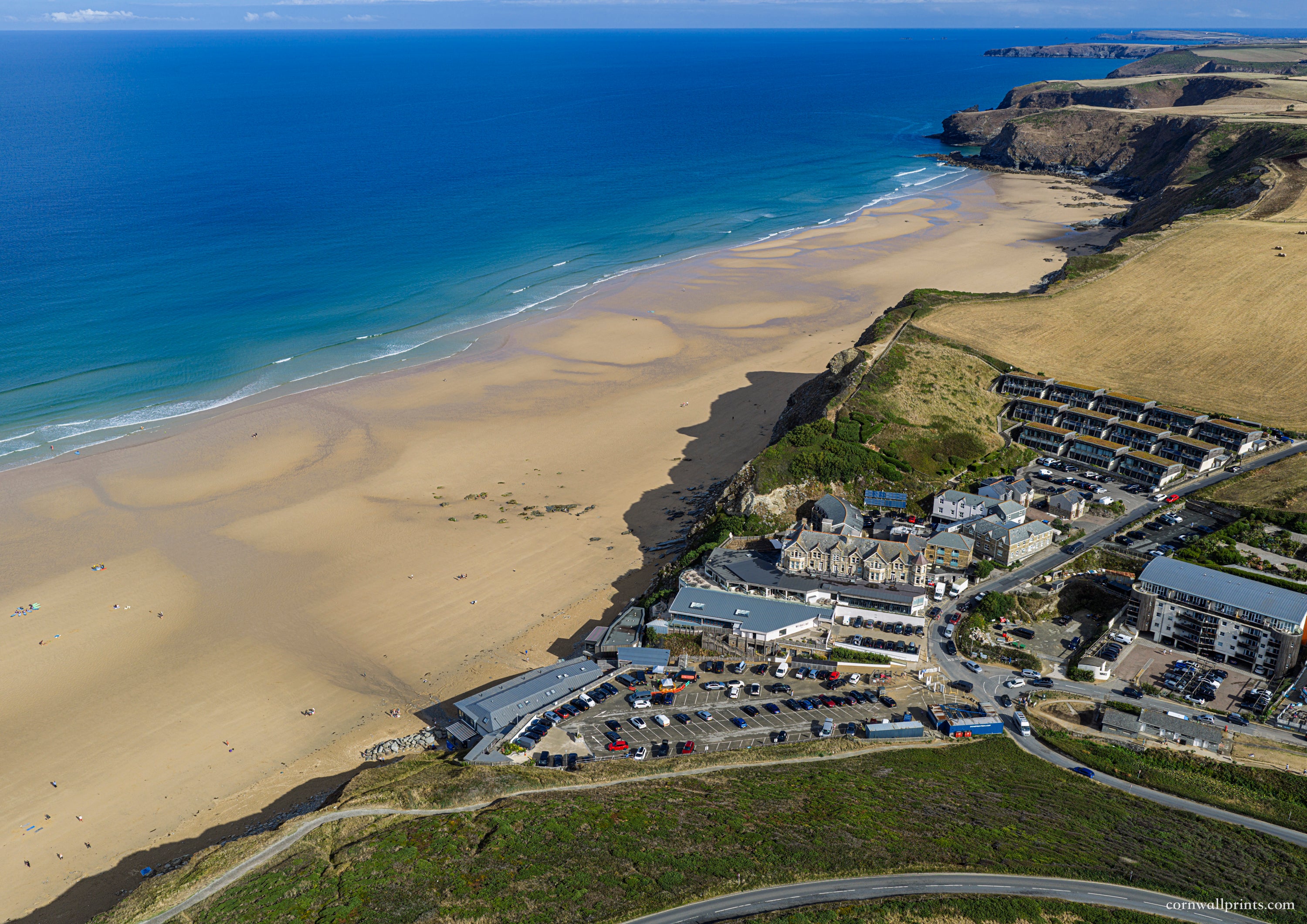 Aerial view of Watergate Bay’s beachfront buildings, cafés and hotels looking north-east along the coast towards Trevose Head