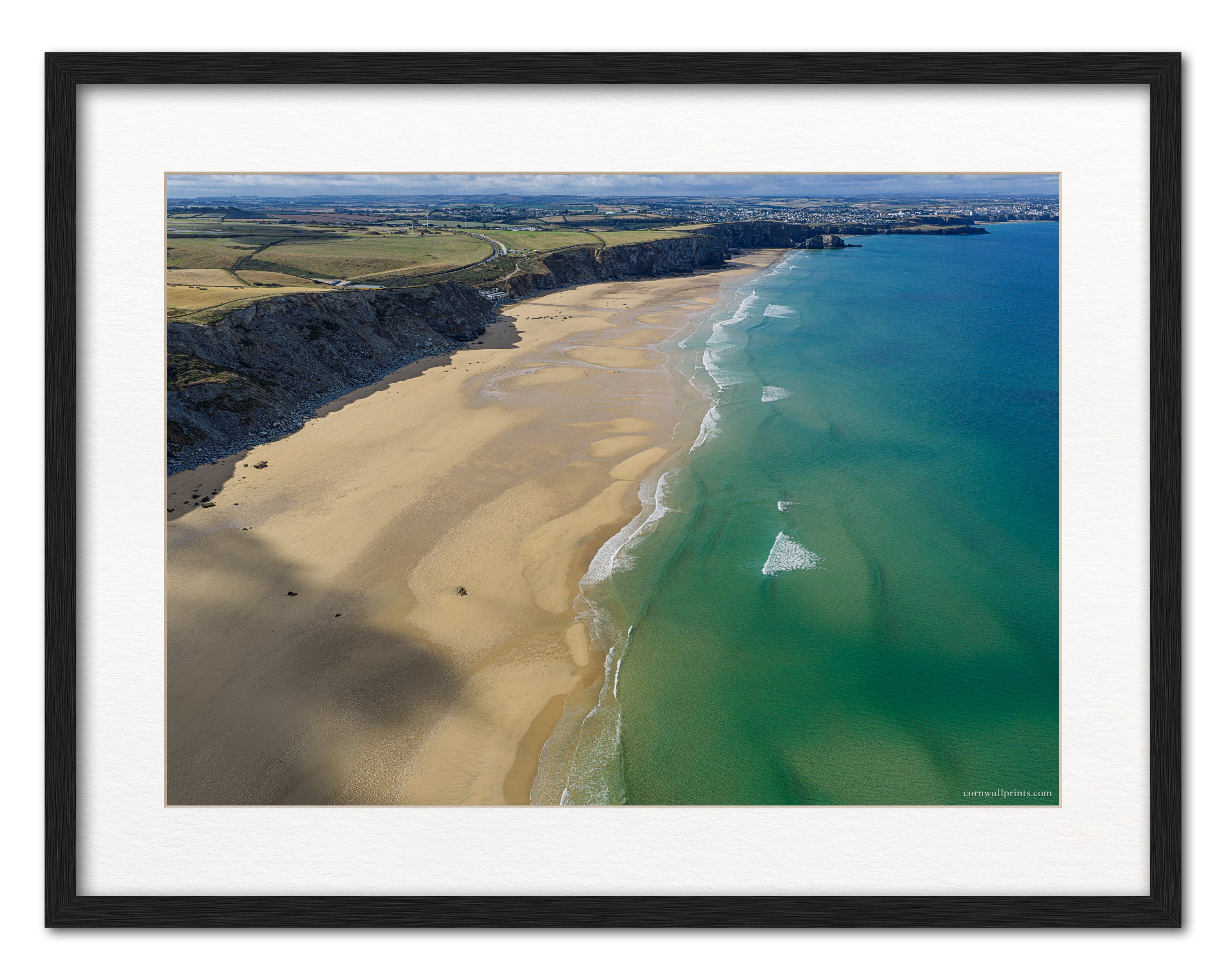 Watergate Bay aerial photograph looking south towards Newquay, displayed in a black frame with white mount