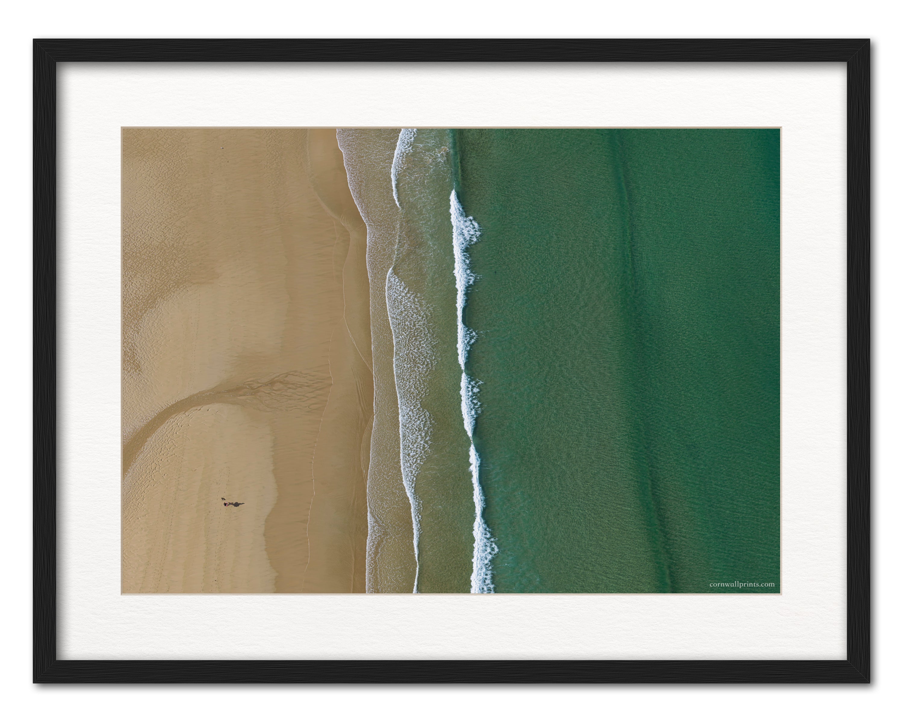 Watergate Bay top-down sand and sea aerial photograph displayed in a black frame with white mount