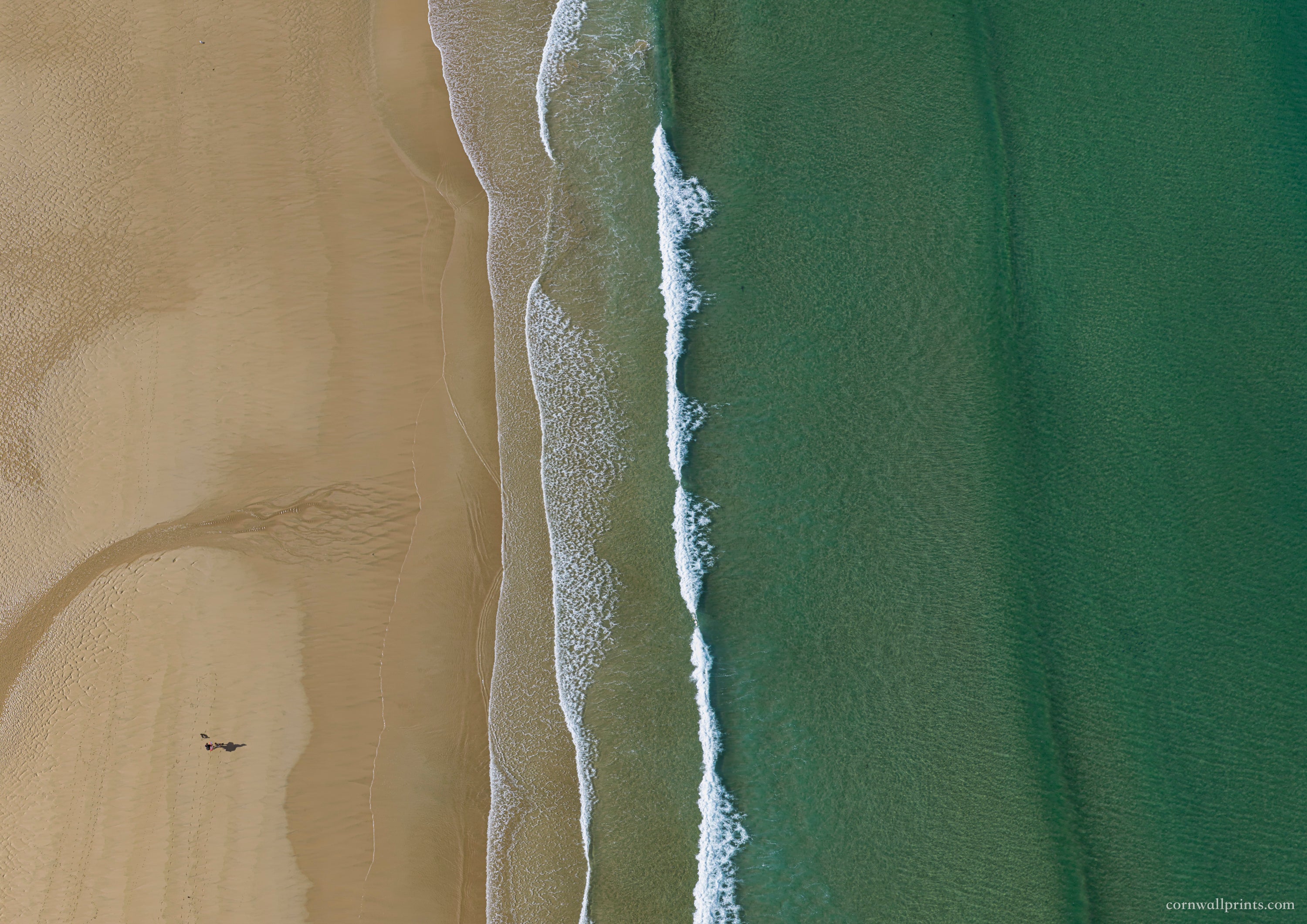 Top-down aerial view of Watergate Bay with textured sand, white surf and smooth turquoise-green water