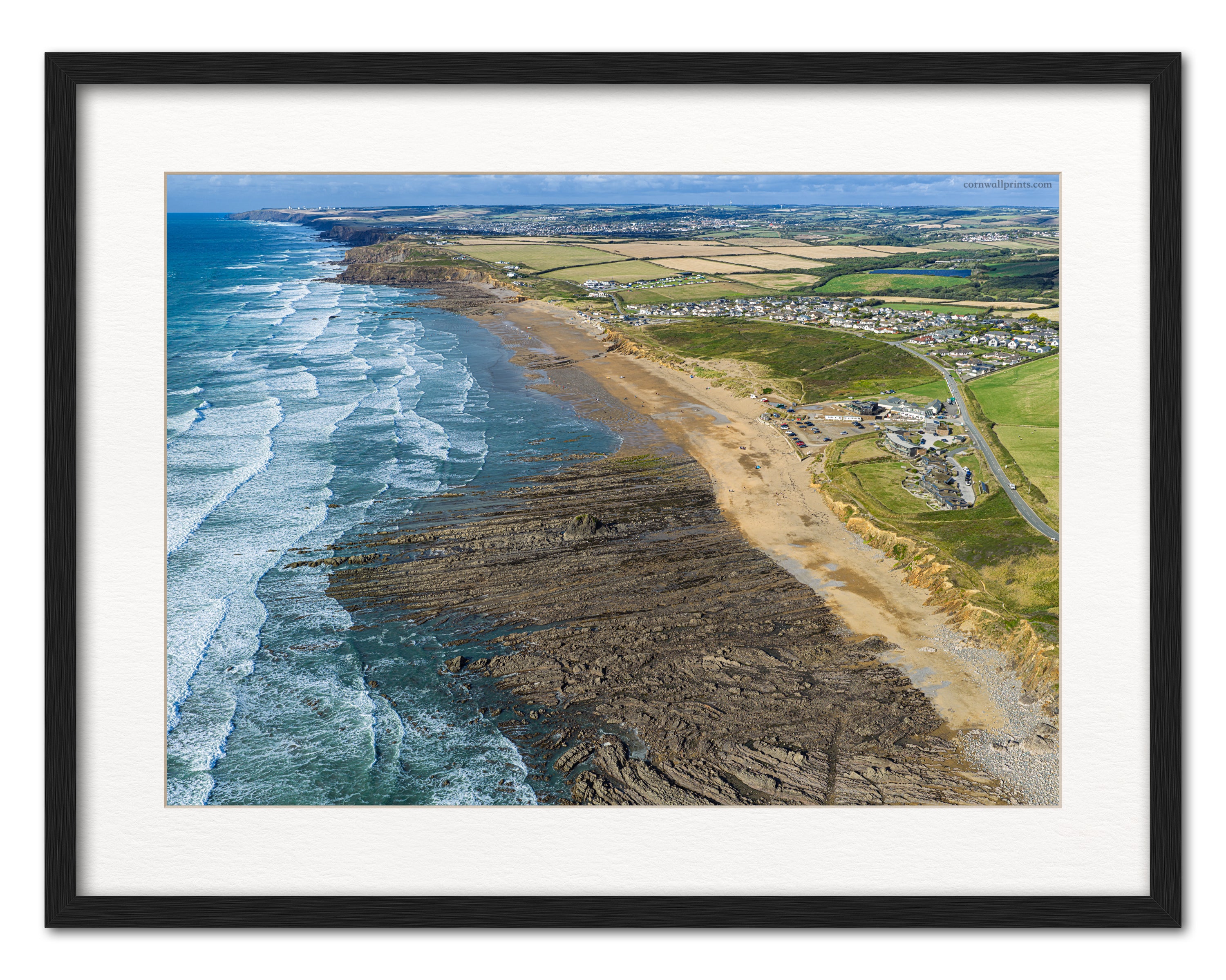 Widemouth Bay aerial photograph looking north towards Bude with late-summer surf, displayed in a black frame with a white mount