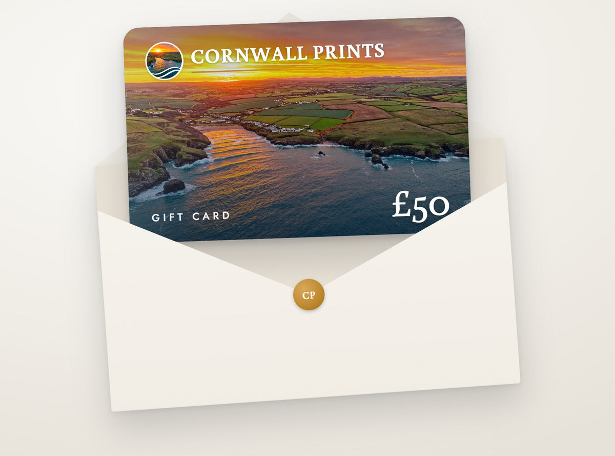 Cornwall Prints gift card with a Porthcothan Bay sunrise photograph, tucked into a cream envelope