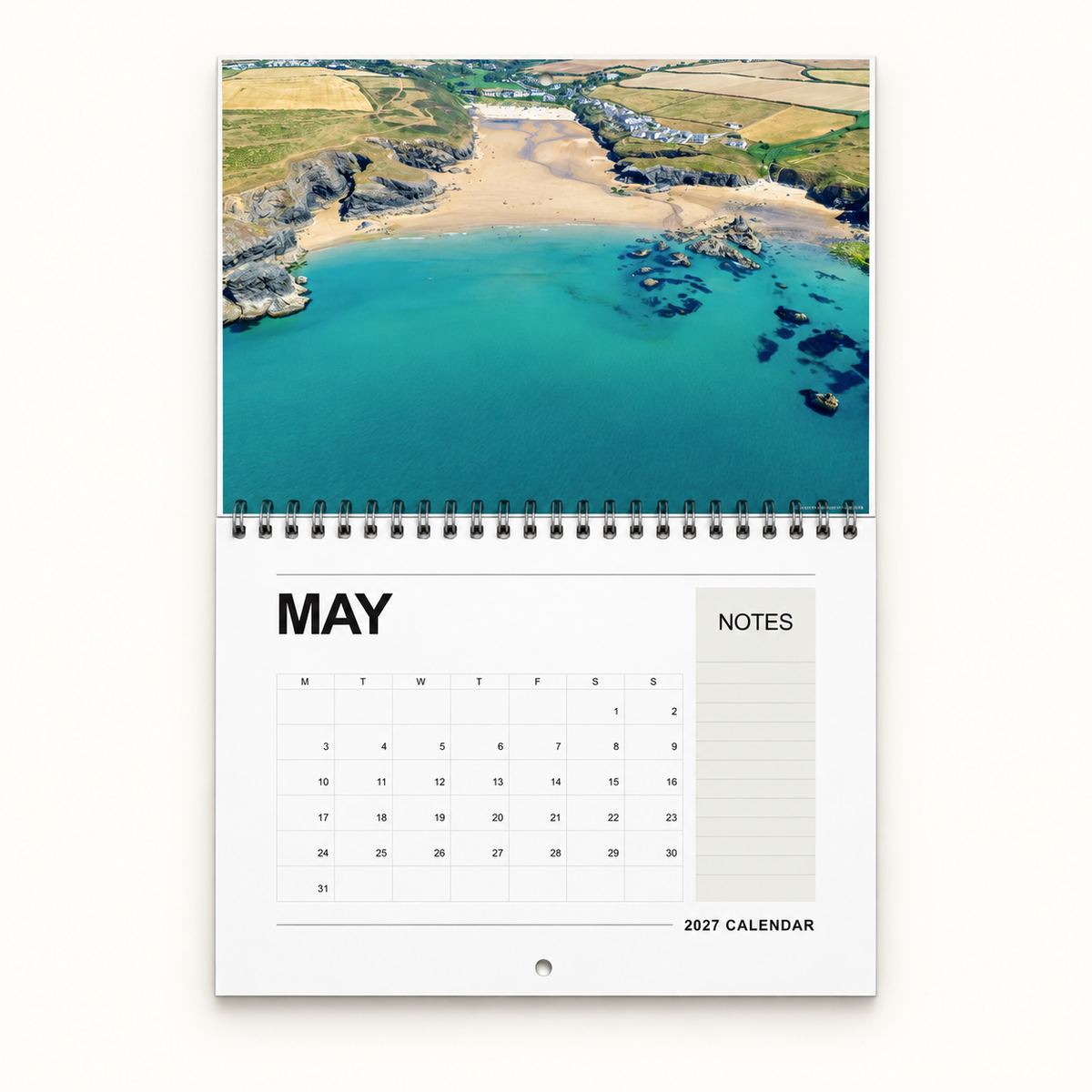 Example personalised Cornwall wall calendar for 2027, showing Porthcothan Bay above the May dates. Choose your own 14 photographs.