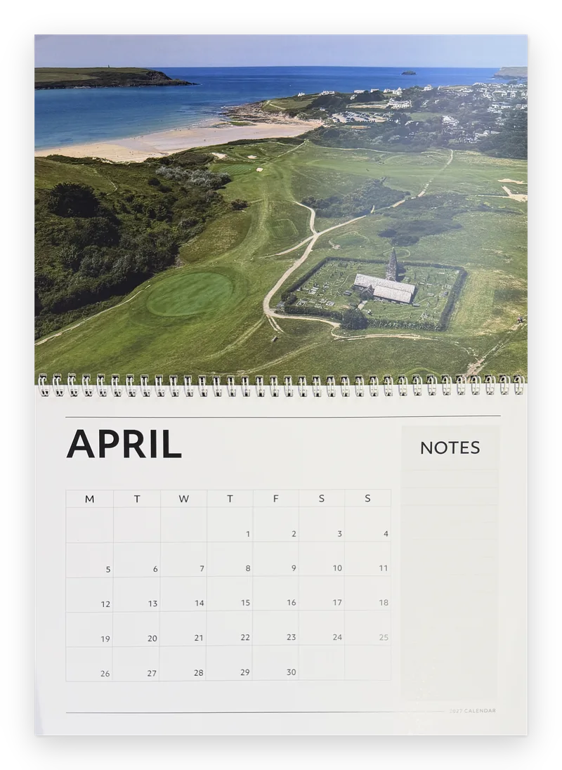 Printed Cornwall calendar 2027 open at April, an aerial golf course and church by the sea above the month grid